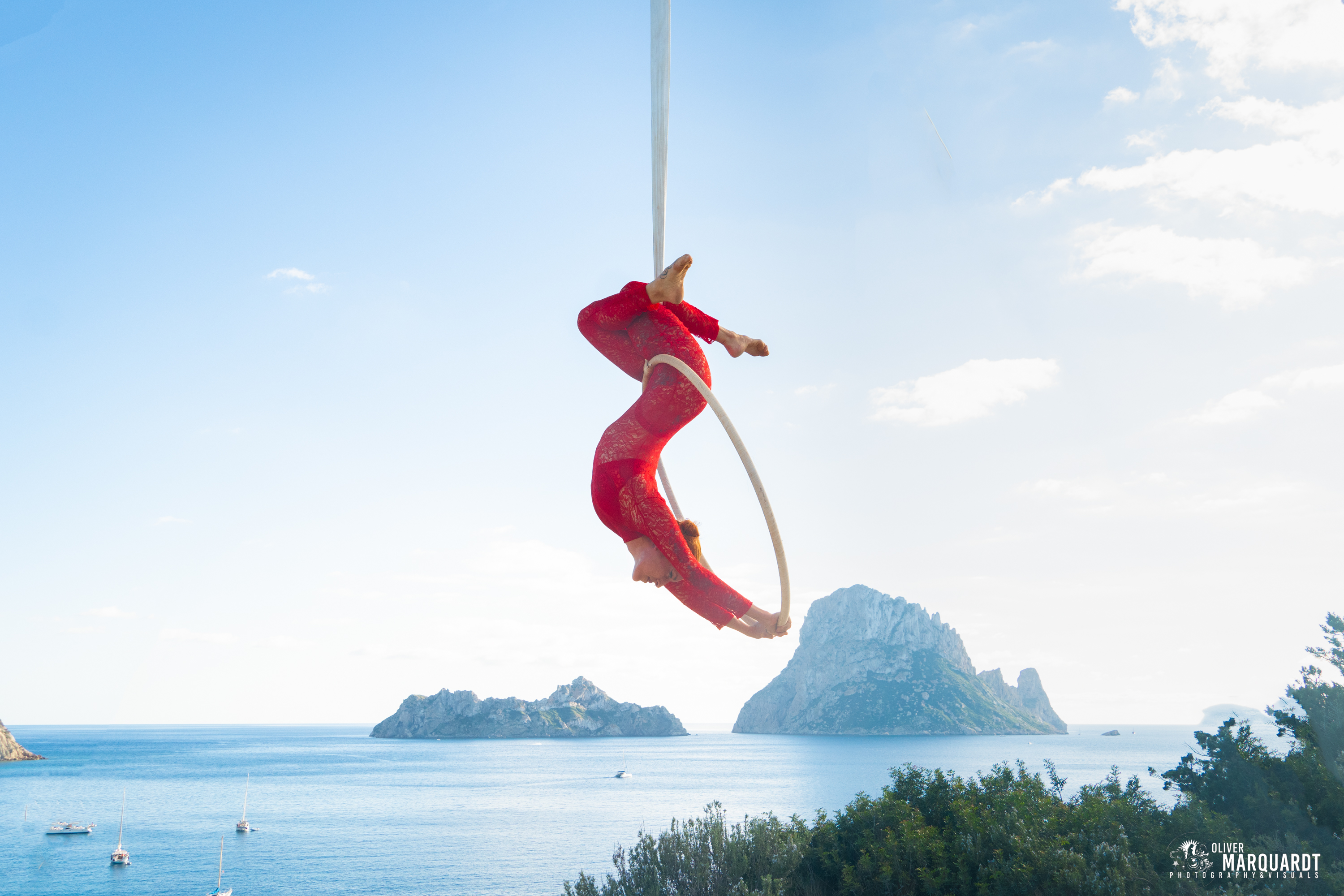 An acrobat in red in an aerial hoop